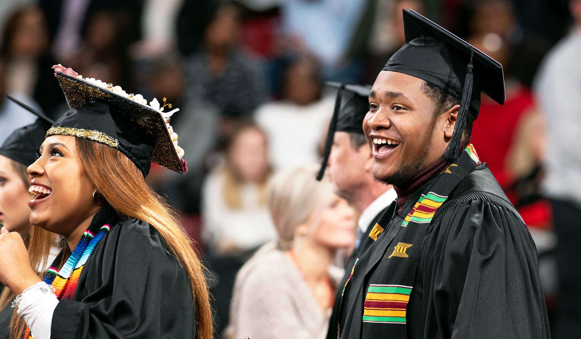 Smiling graduates in cap and gowns during processional