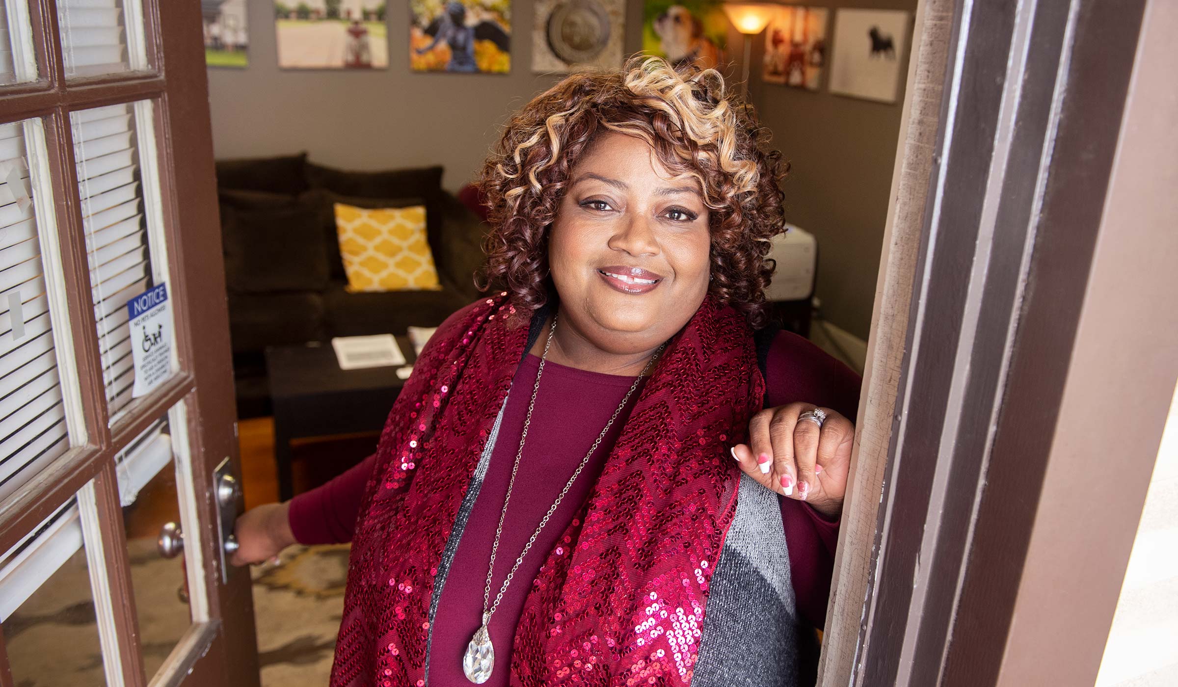 Aretina Hankerson-Daniels, pictured in a maroon dress standing in the doorway of her office