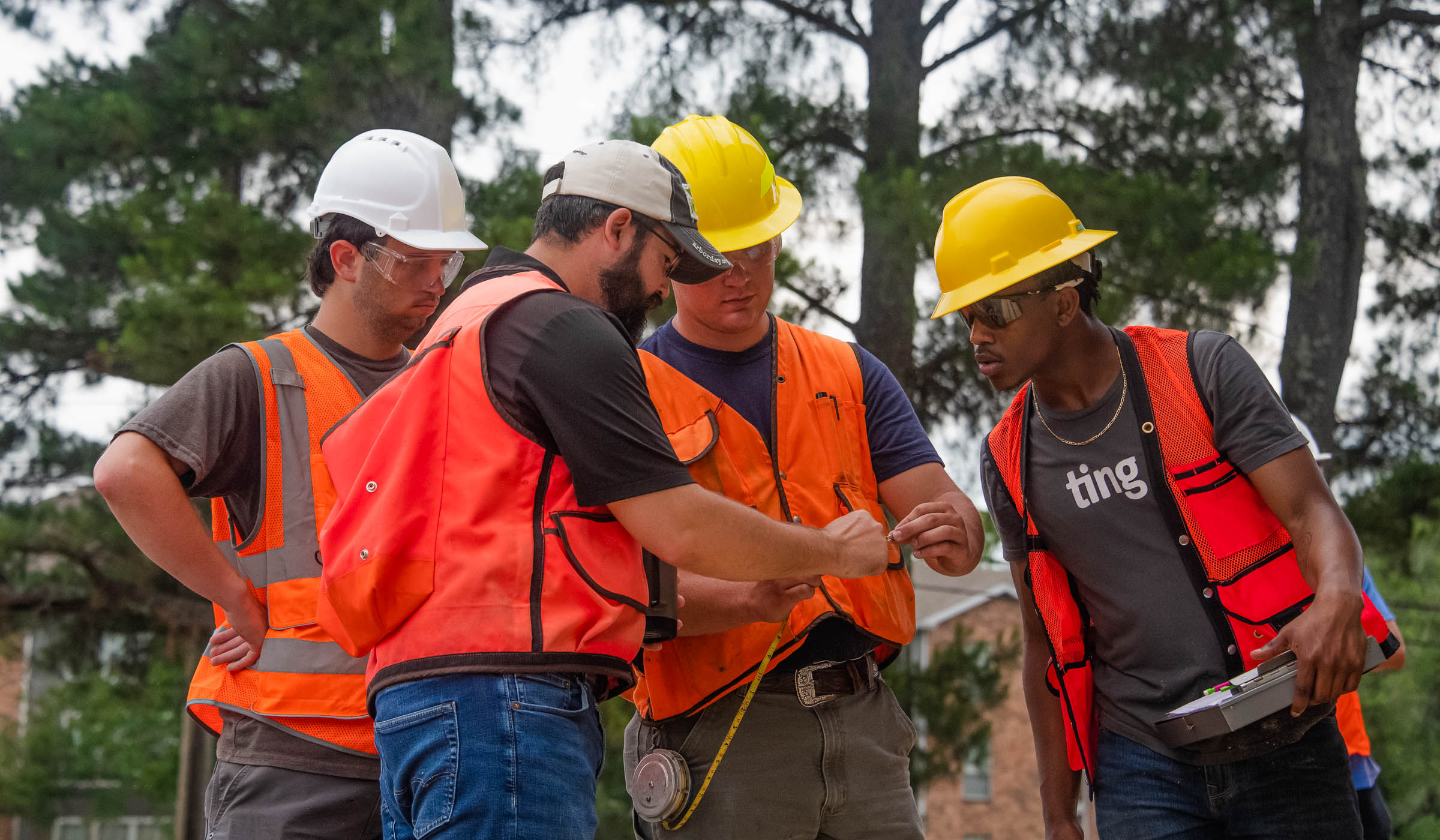 Men in construction vests reviewing tape measurement