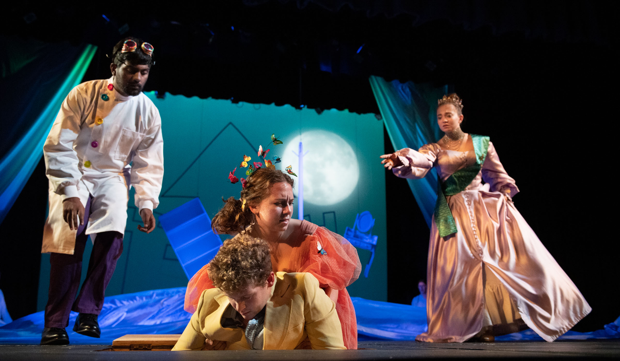 The actress playing The Light Princess pulls her beloved from below stage while two other characters react to the scene.