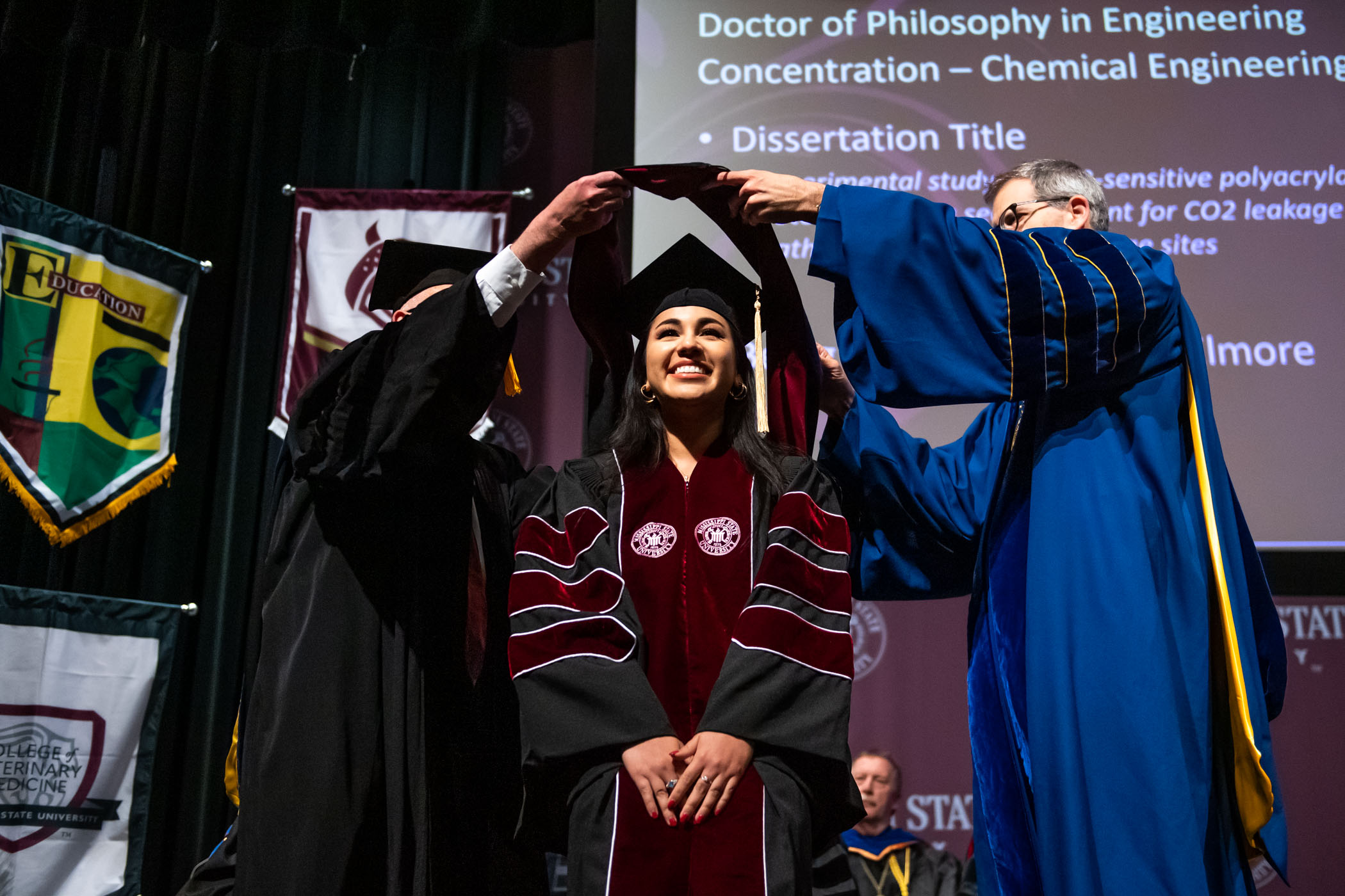 A female PhD recipient bends down to be hooded at MSU&#039;s Doctoral Commencement Ceremony