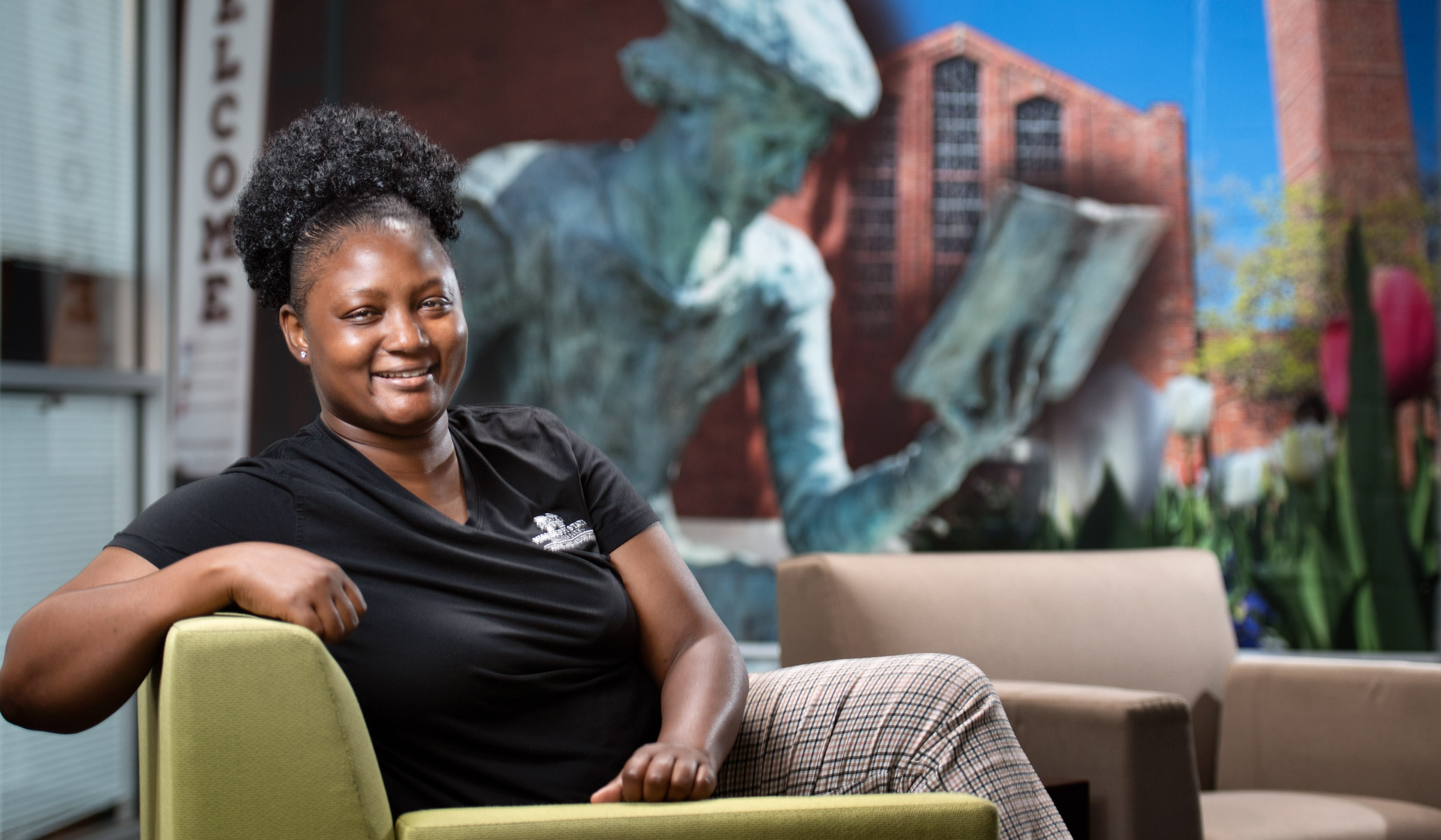 Dominque Sessums, pictured sitting in a chair in front of a mural