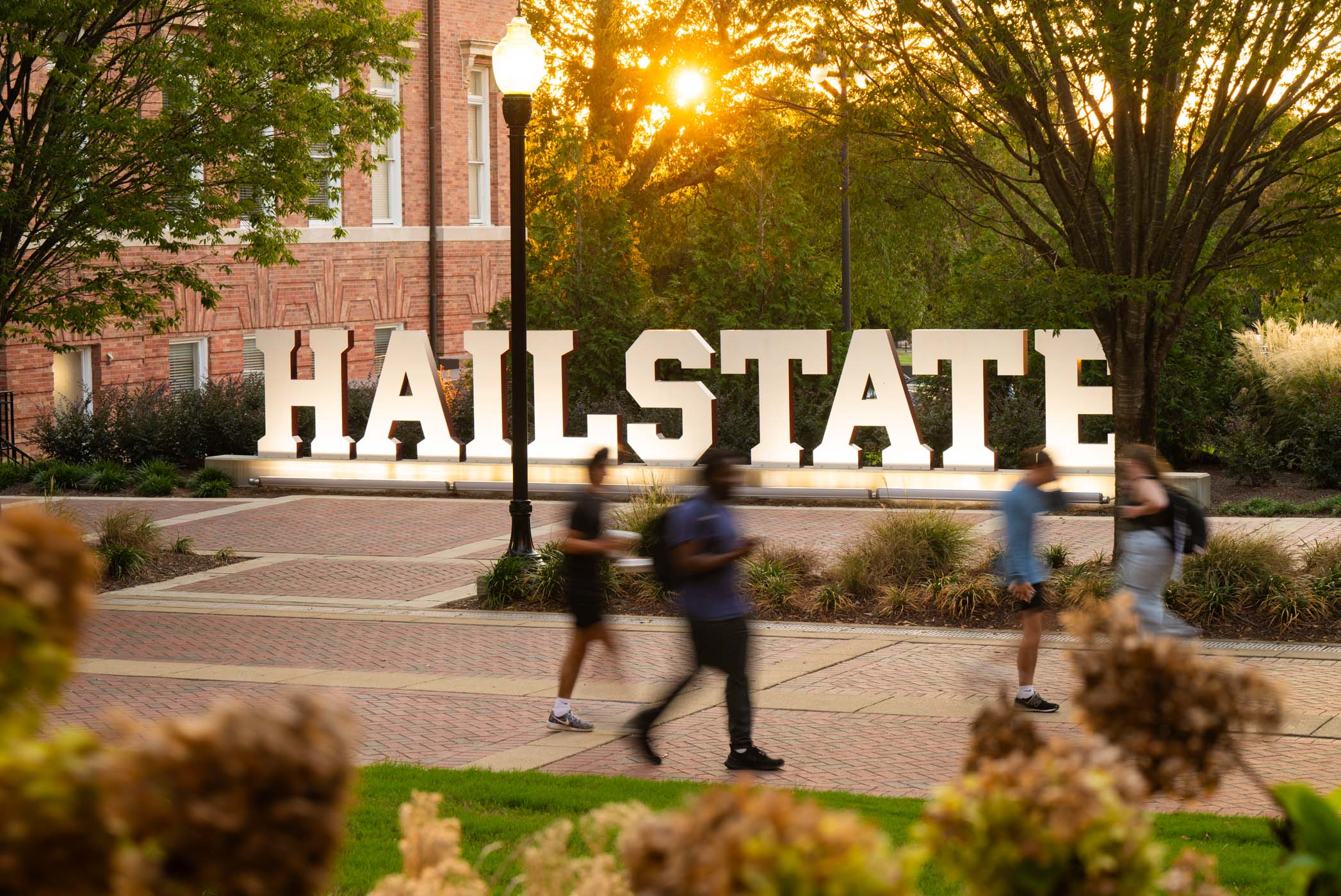 The sunsets over the Hail State sign as students enjoy an evening walk on campus.