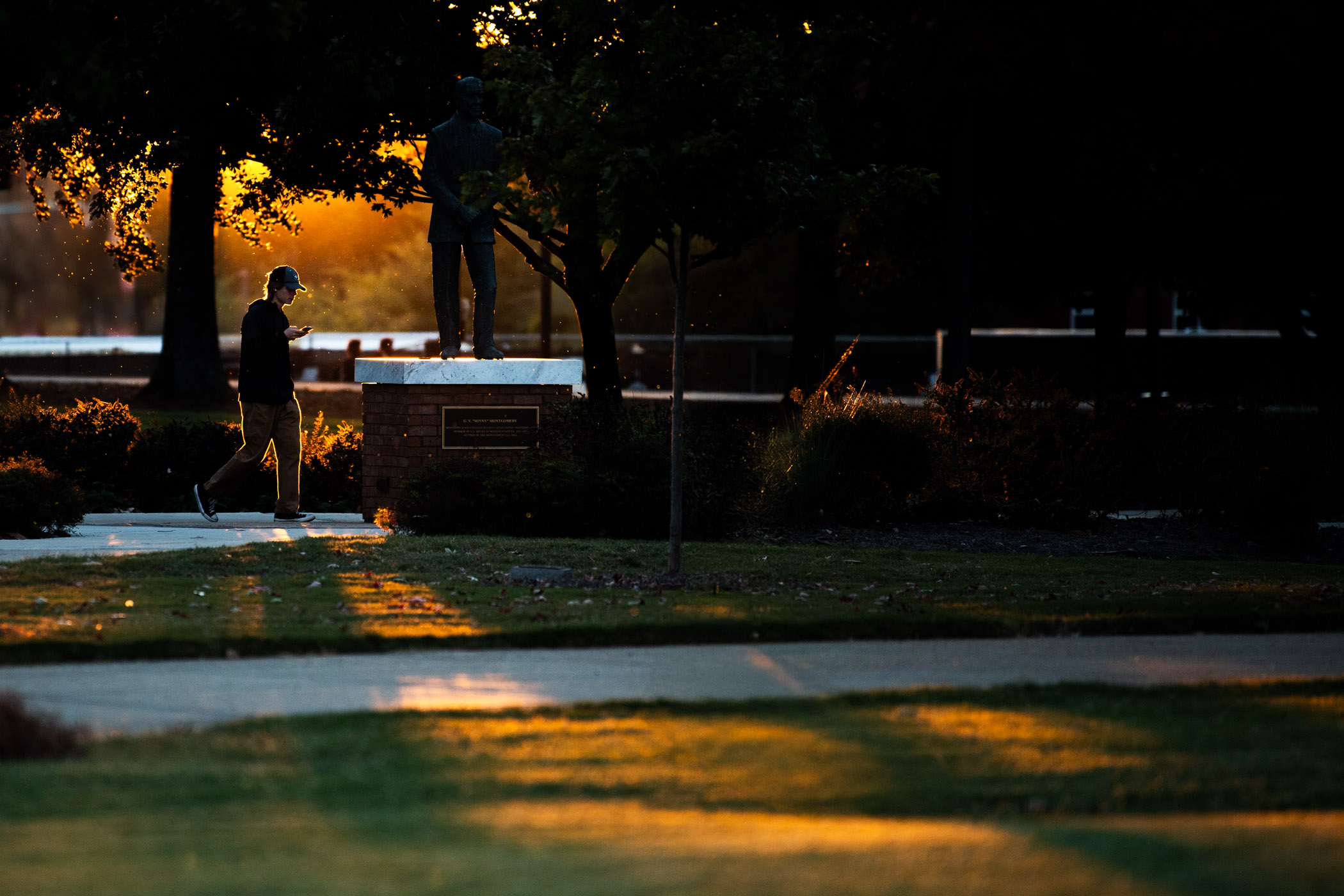 A benefit from &quot;falling back&quot; as part of daylight saving time, rich golden light outlines a strolling passerby and highlights campus with an early sunset. 