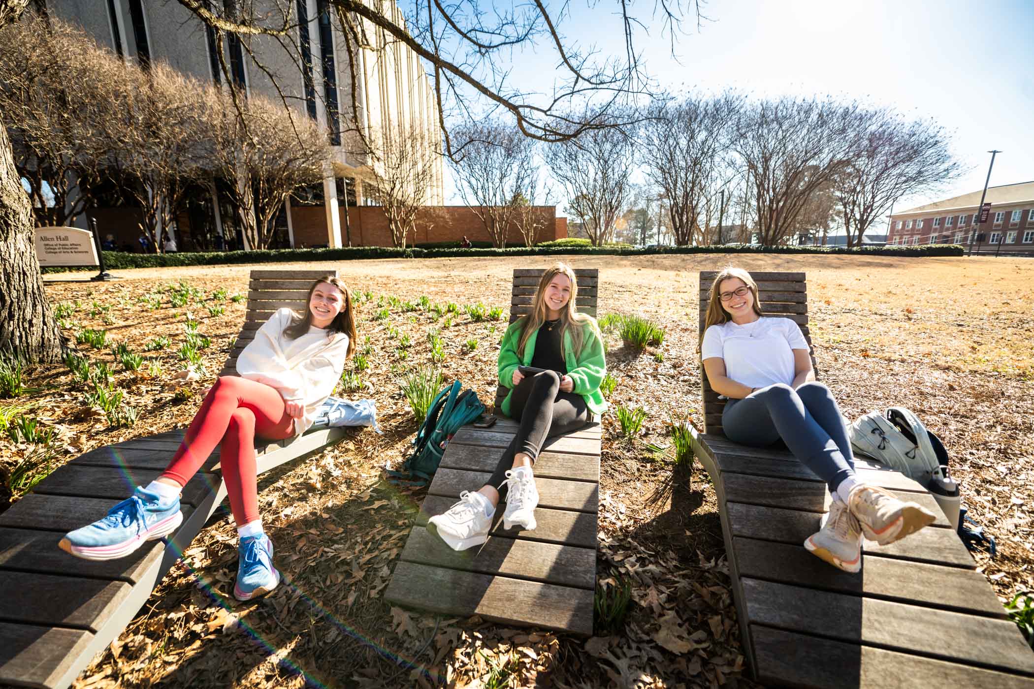 Sophia Jones, a freshman Kinesiology student from Greenville (left.) Lilly Grace Taylor, a junior psychology student from Gulfport (middle,) and Morgan Dees, a junior psychology student from Greenville (right,) enjoy each other&#039;s company on a beautiful afternoon [Feb 25] while lounging on Allen Hall&#039;s adirondack chairs. Like Sophia, Lilly Grace, and Morgan, MSU students are taking a relaxing pause in the midst of a busy semester, with a long-awaited spring break from March 10 to 14.