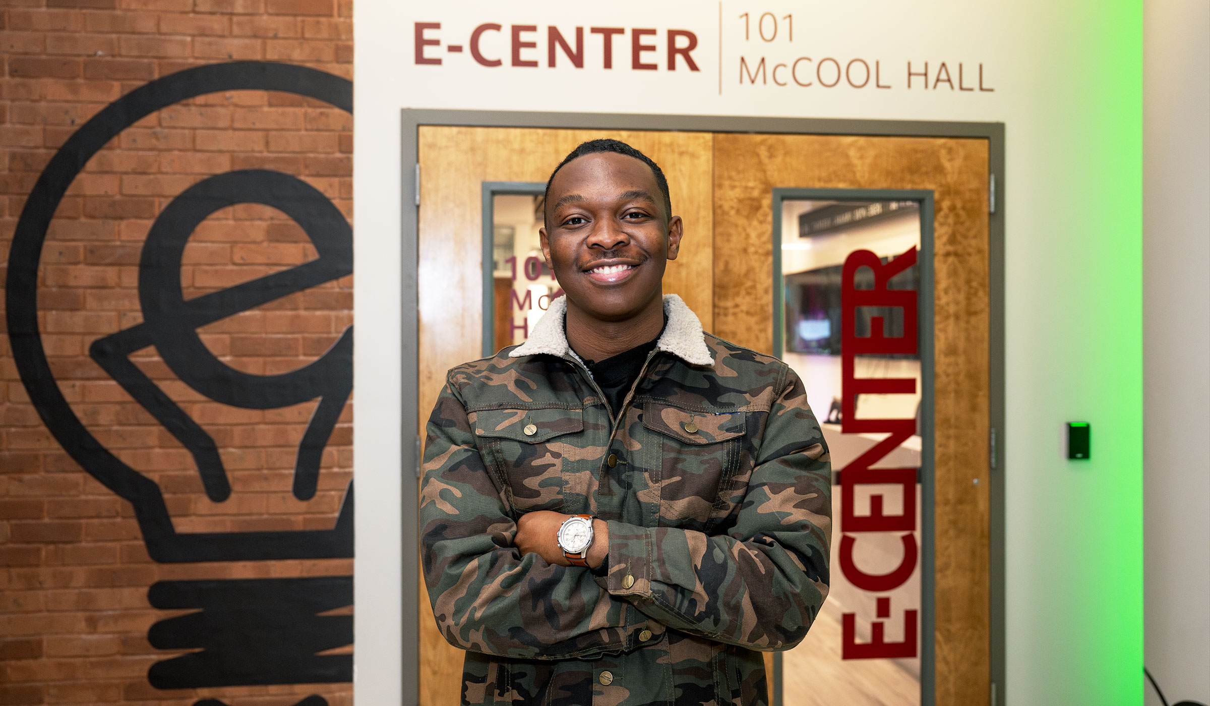 young man standing with his arms crossed in front of a wooden door