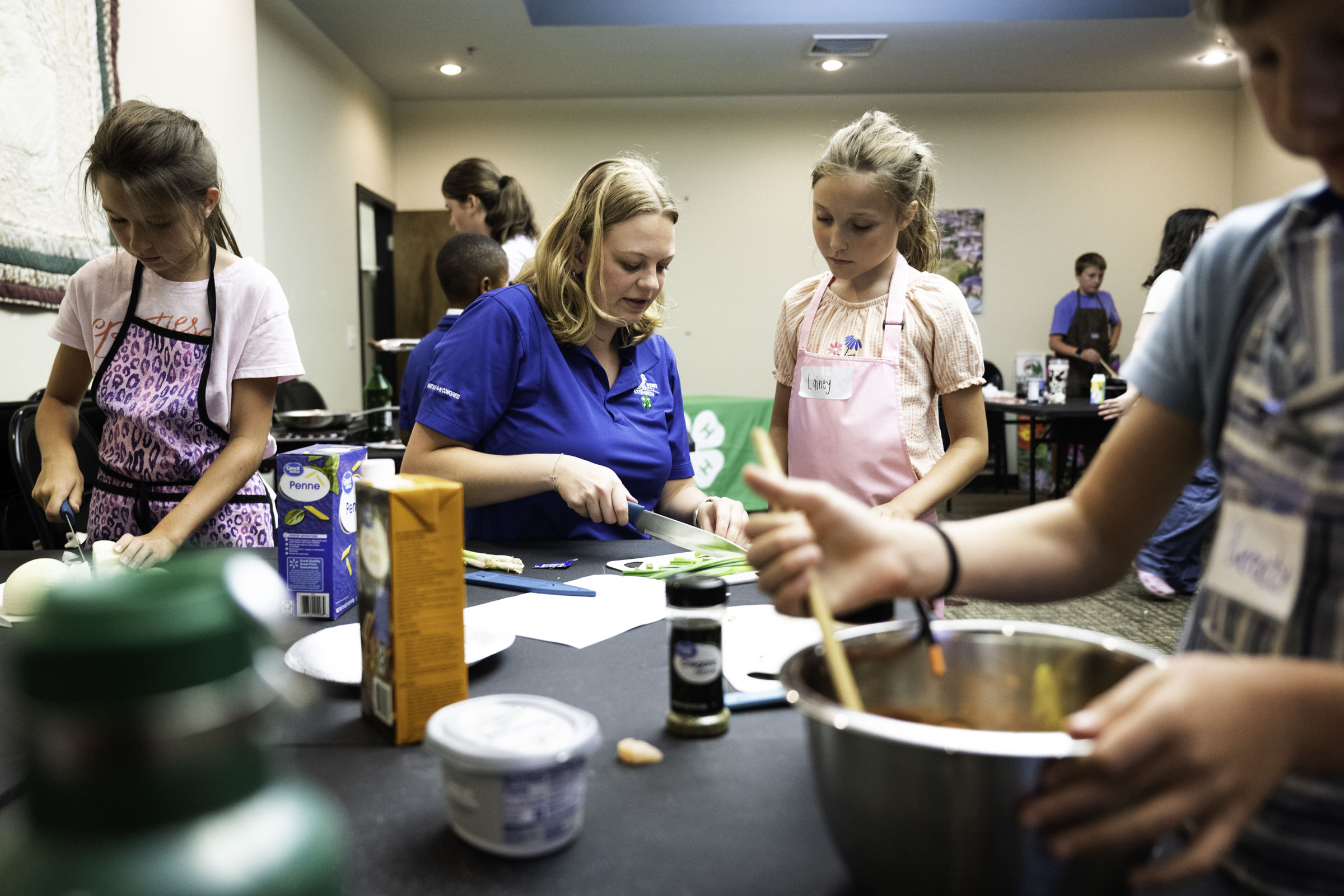 MSU Extension Culinary Camp Director Breanna Keowen demonstrates to camp participant Lainey Taylor how to chop green onions during the program's camp cook-off, where young aspiring chefs put the culinary skills they learned throughout the week to the test. Hosted by Mississippi State University Extension Service, the annual camp introduces students to food preparation, kitchen safety, nutrition and teamwork through hands-on cooking experiences designed to build confidence in and out of the kitchen.