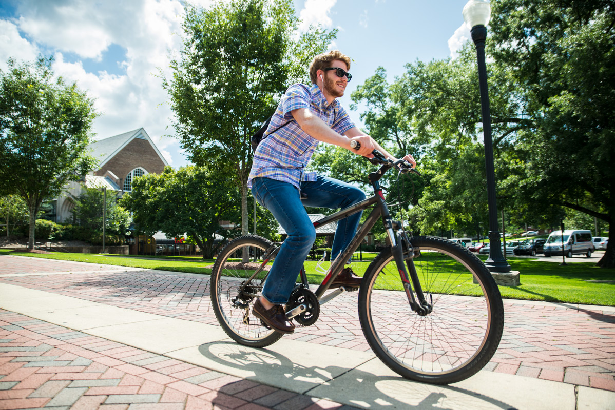 Ben Caldwell bikes on campus on a hot summer day