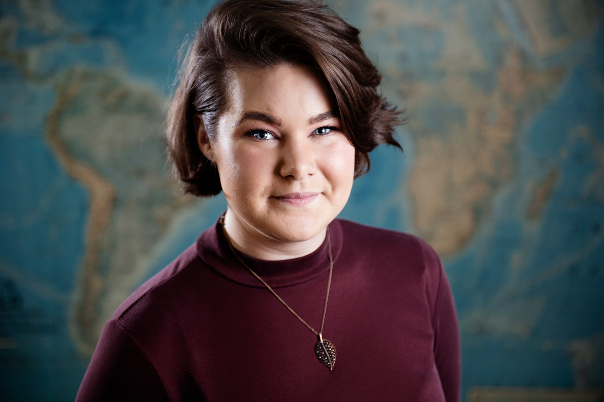 Madeline &amp;quot;Maddie&amp;quot; Casey, pictured in front of a global map.