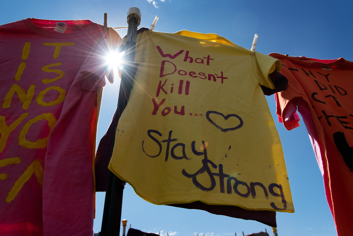 A yellow t-shirt handing from a clothesline reading &amp;quot;what doesn&amp;#039;t kill you... stay strong&amp;quot;