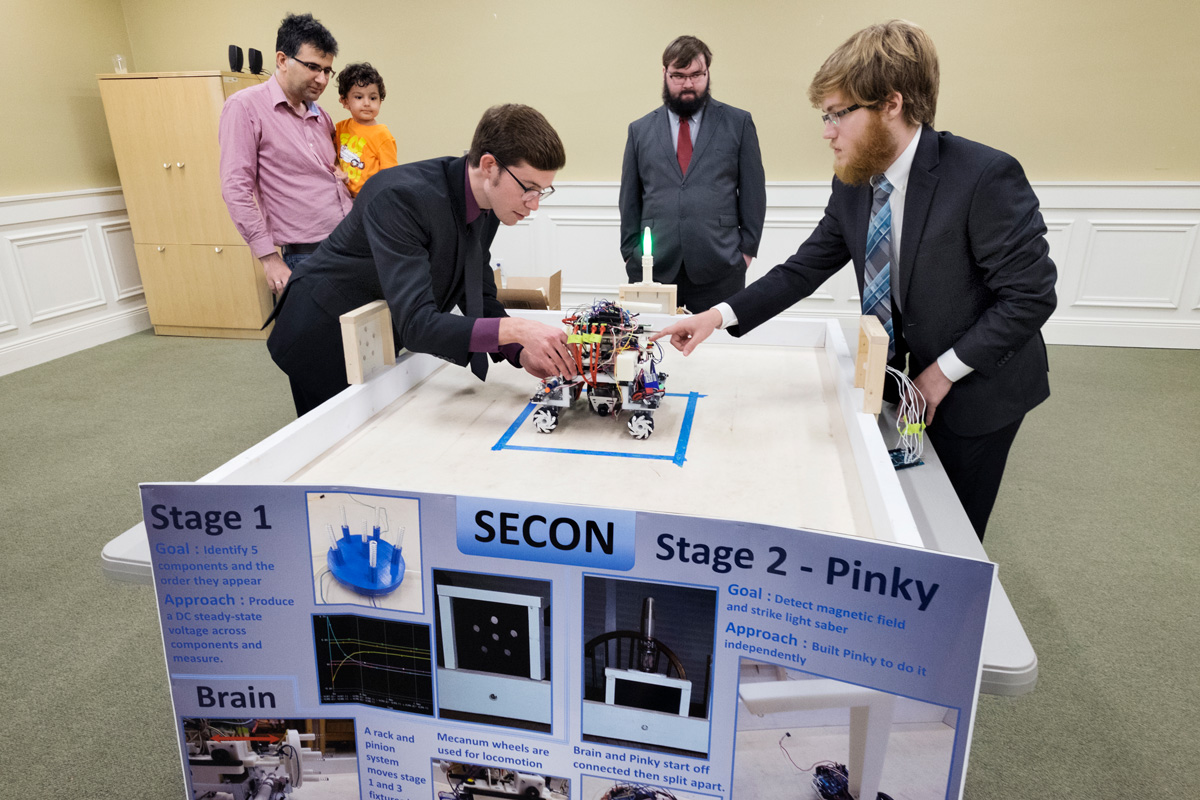 Senior Electrical and Computer Engineering students demonstrate robot project to Professor Kurum.