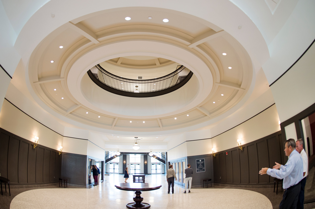 Staff touring the new Old Main Acadmic building interior hallway are dwarfed by the dramatic circular balcony overhead.