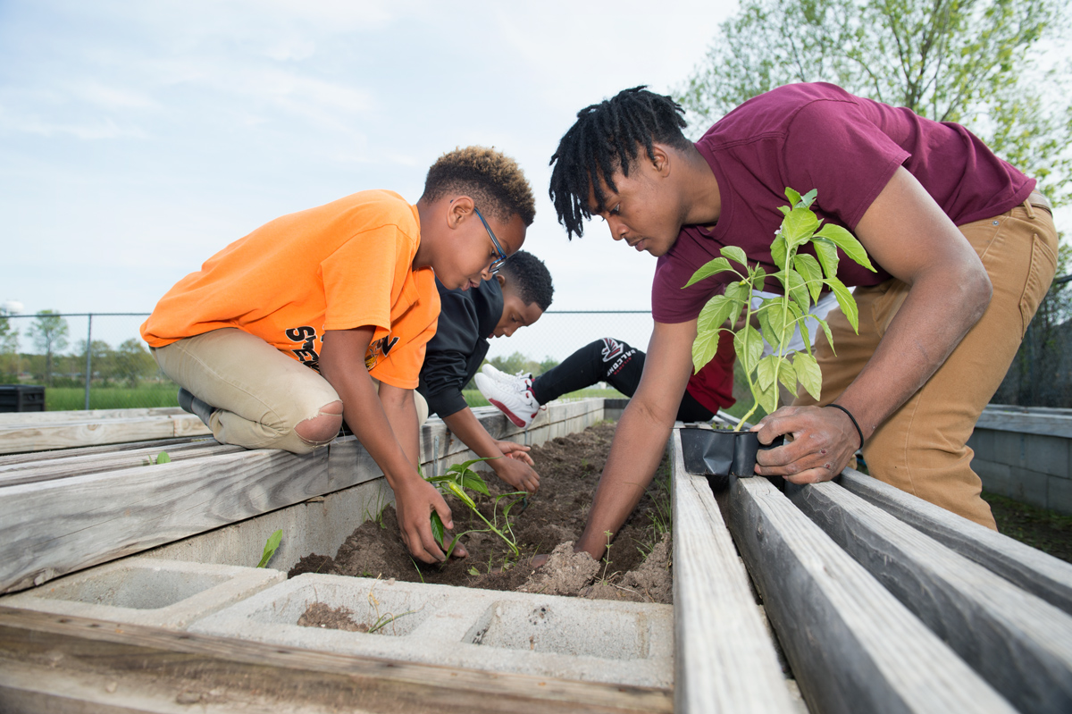 Architecture student Jordan Smith digs in the dirt with Boys and Girls Club children as they add the first plants of the season.