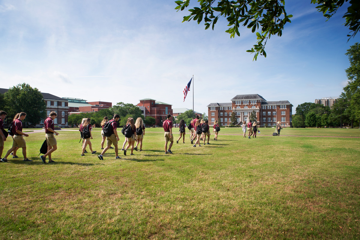 Team of Orientation Leaders cross the grass of the Drill Field toward a photoshoot near Swalm.