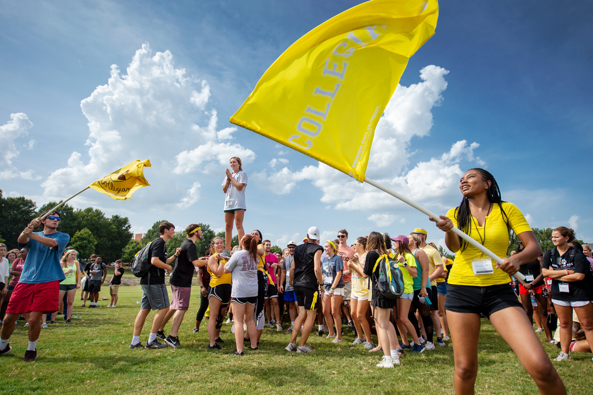 Members of the New Maroon Camp Collegiate team cheer and wave yellow flags before the Family Olympics event.