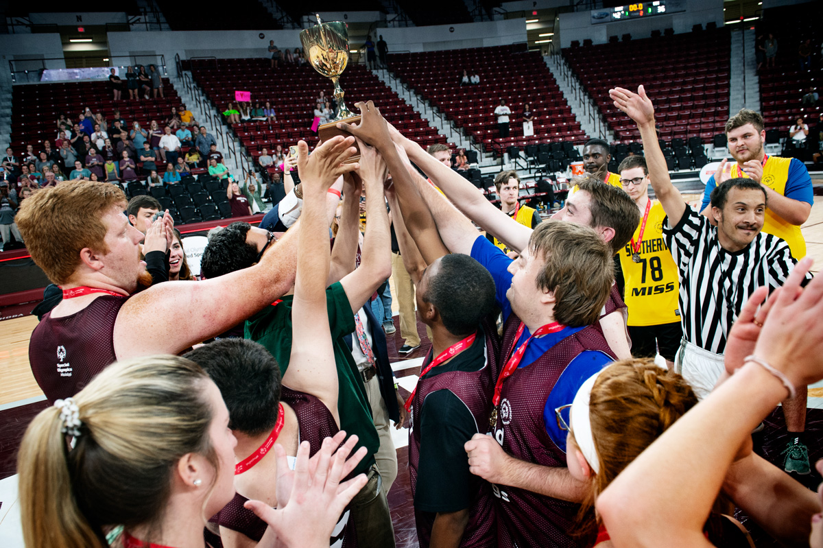 ACCESS Program basketball players hoist the Magnolia Madness trophy in the air in celebration at the Hump.