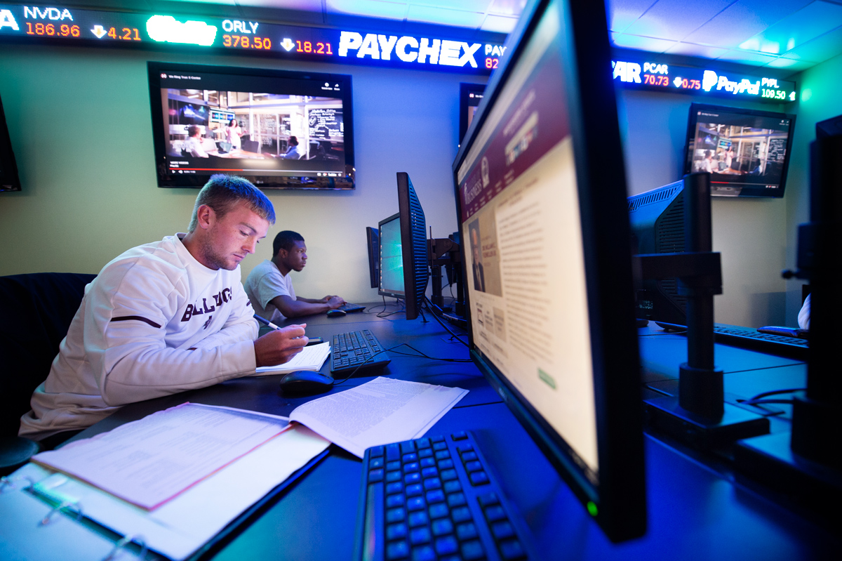 With the stock market ticker tape in the background, Niclas Braun and Joshua Wright work on computers in the Finance Lab.