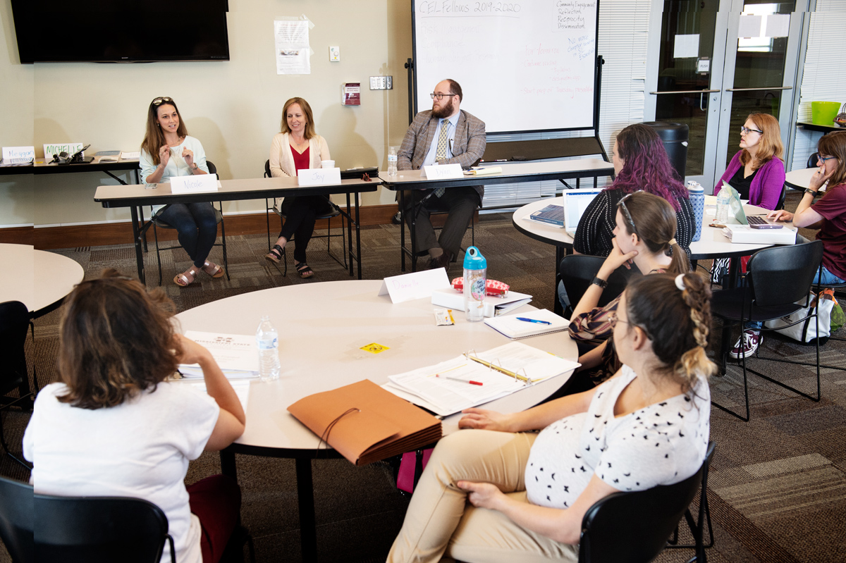 Panelist Nicole Cobb (left) speaks while the other two panelists and CEL faculty fellows listen from round tables.