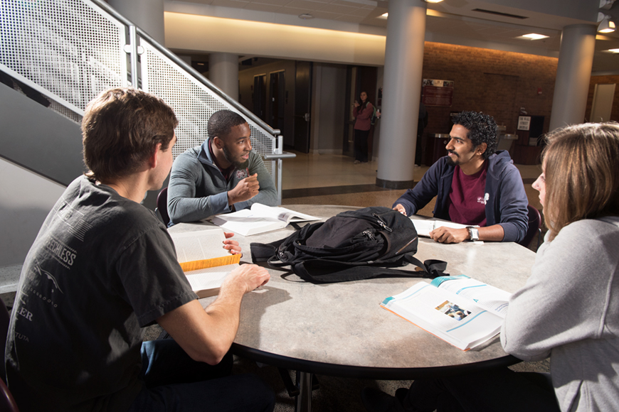 A group of people studies together at a round table.