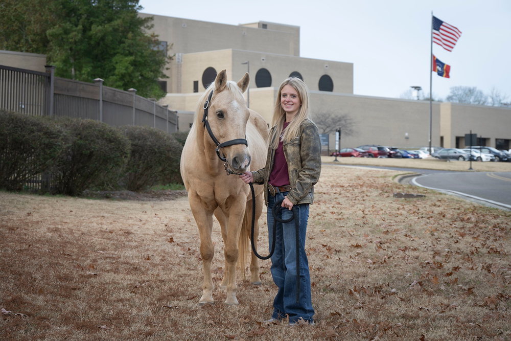 Joy Nabors, pictured with a horse in front of MSU's College of Veterinary Medicine