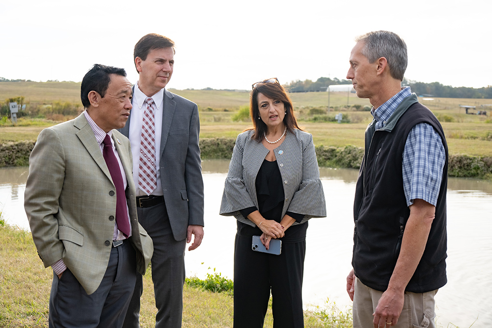 Scientists talk in front of an aquaculture pond