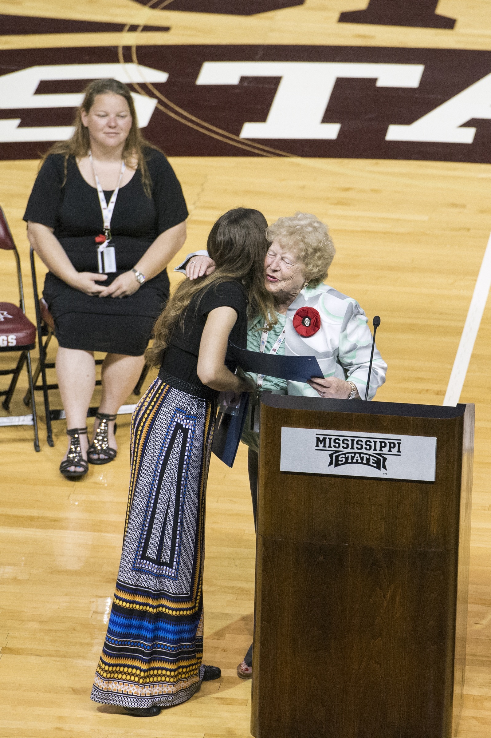 As director Brooke Cullen Smith (seated) looks on, Mary Barrett (right), American Legion Auxiliary Department of Mississippi president, congratulates Marisa Laudadio of Walnut for being chosen Girls Stater of the Year. The Girls State gathering at Mississippi State concluded Friday [June 12] with an awards ceremony at the university's Humphrey Coliseum.