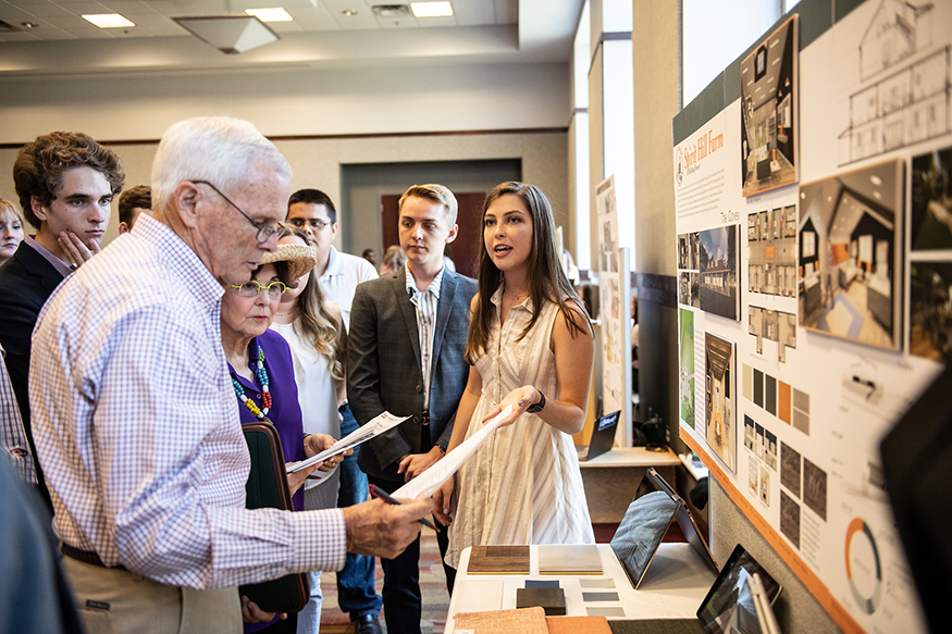 Students look on as Olivia Baker presents her team’s Spirit Hill Farm barn renovation project to MSU alumni Bob and Sheryl Bowen.