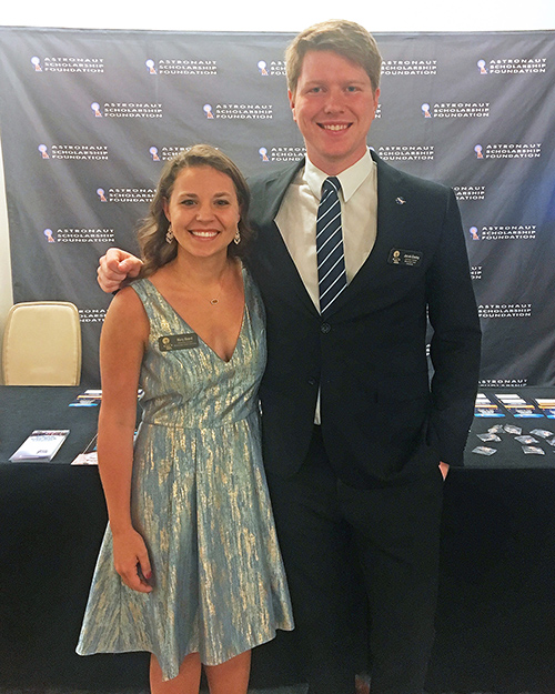 A young lady and man dressed up for a special event smile in front of an Astronaut Scholarship Foundation backdrop