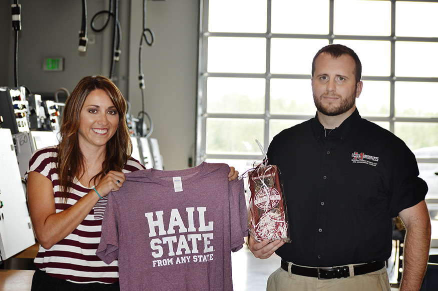 A woman holds an MSU T-shirt and a man holds an MSU cowbell.