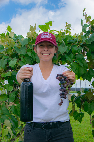 Haley Williams holding grapes and a wine bottle