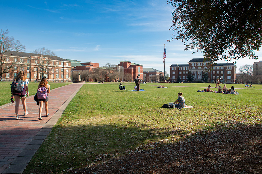 Students walk across the Drill Field on a sunny spring day