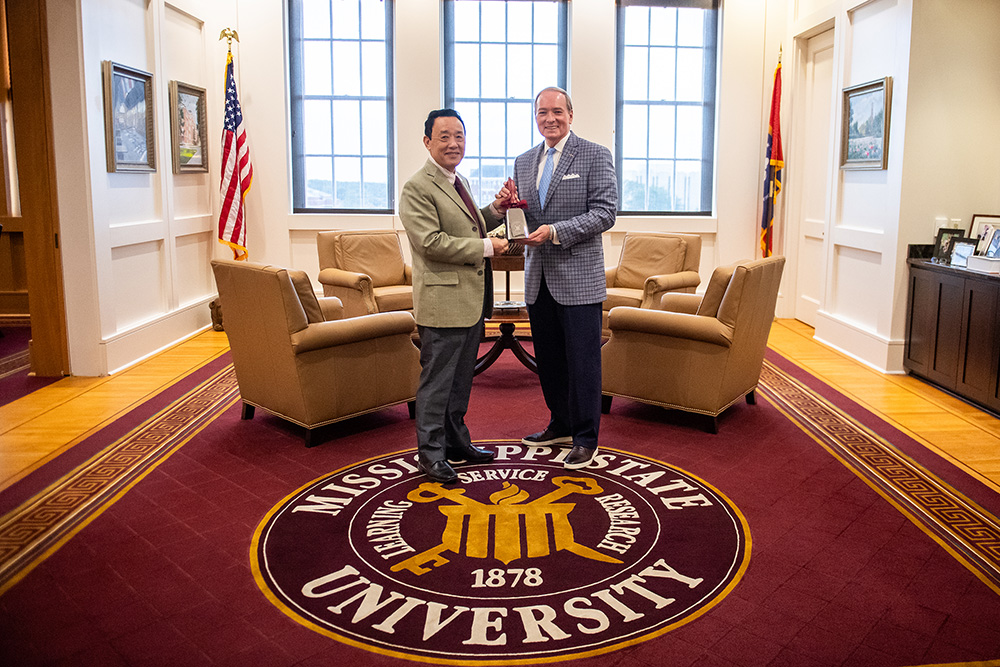 Mark E. Keenum presents a cowbell to Qu Dongyu