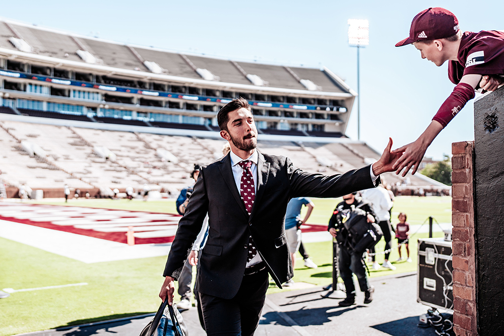 Nick Barr-Mira high fives a fan while walking on the field. 