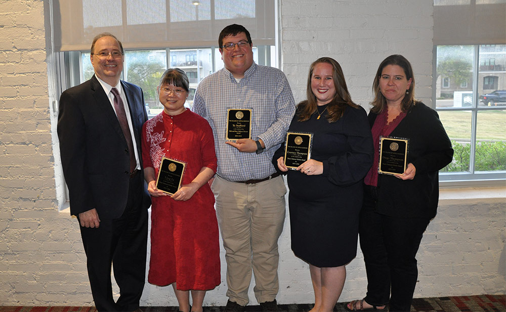 Dean of the College of Arts and Sciences Rick Travis, left, presents 2023 fall faculty awards to Ling Li, Ty Stafford, Courtney Thompson, and Kimberly Kelly, who received the award on behalf of Diego Thompson. 