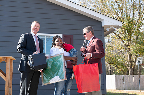 Cadence Bank’s Jerry Toney and Paul B. Murphy Jr. present bags of homeowner gifts to Starkville resident Keva Robertson and her son Laquante
