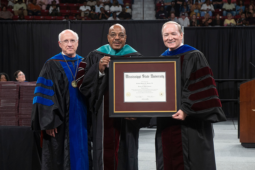 MSU Provost and Executive Vice President David Shaw, left, and President Mark E. Keenum, right present Col. Robert L. Barnes Jr. with an honorary Doctor of Public Service degree. A 1972 MSU graduate, Barnes was the first African American ROTC cadet to be commissioned into the U.S. Army from MSU. He would go on to retire at the rank of Colonel in 2004. (Photo by Beth Wynn)