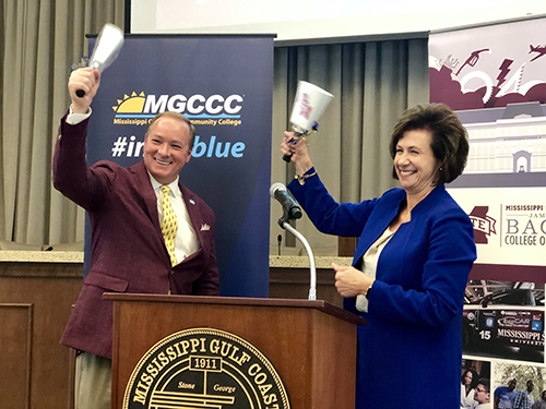 Mark Keenum and Mary Graham ring matching cowbells at a podium.