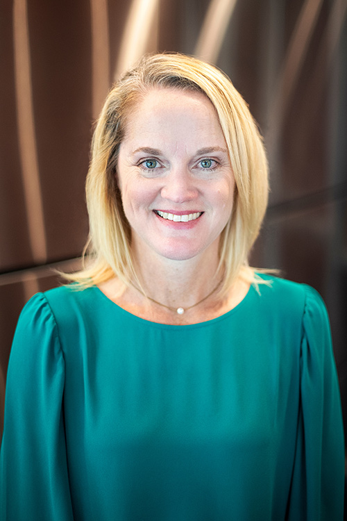 An up-close portrait of Leann Markham wearing a teal shirt and single pearl necklace