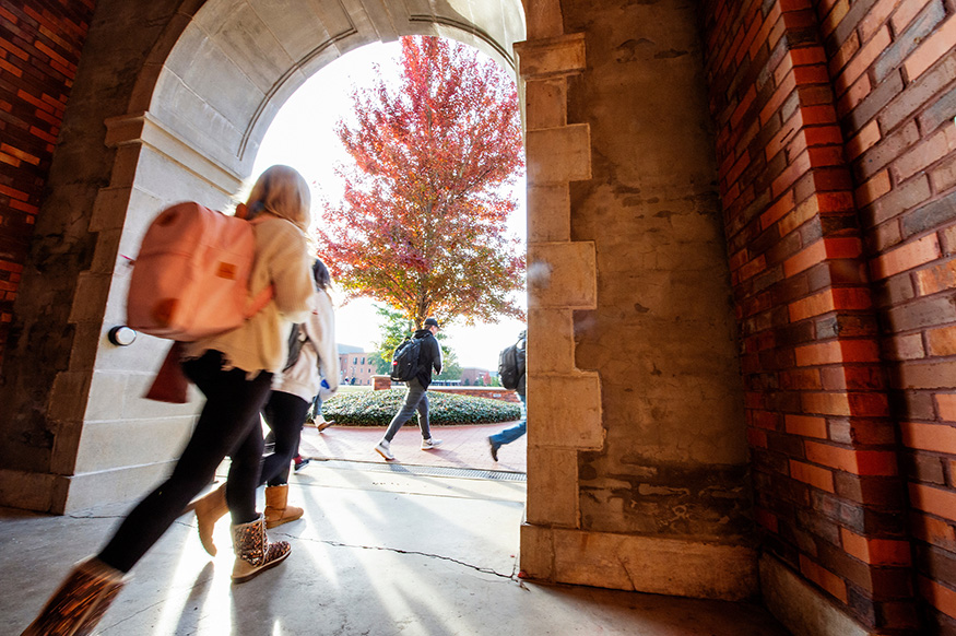 A student walks under the arch at McCain Hall on a crisp fall day.