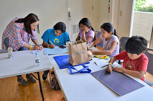 A Mississippi Migrant Education Service Center volunteer assists children with a reading and drawing exercise during a Parental Advisory Council meeting at the Mississippi Children’s Museum in Jackson.