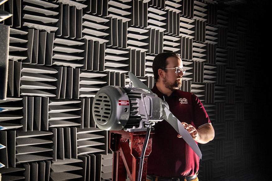 Raspet Flight Research Laboratory engineer Hunter Vesa grasps a propeller while standing inside the acoustic anechoic chamber