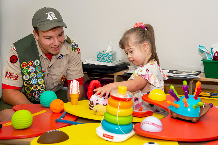 Matthew Daves shows one of the sensory boards he made to preschooler Hannah Johnson.