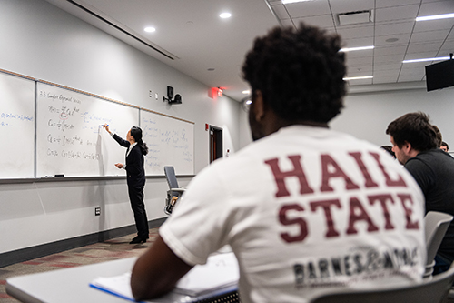 A teacher writes on a board in an MSU classroom