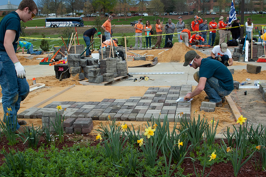A student works on a hardscape installation with pavers outside