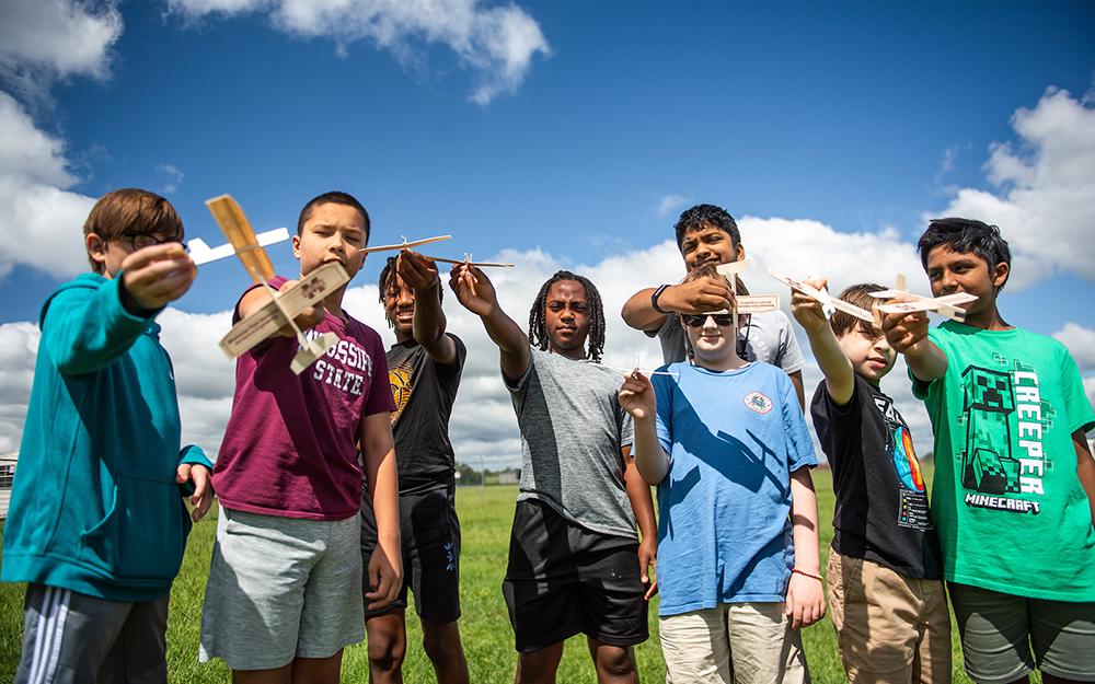 Participants of the Mississippi State Advanced Composite Institute summer camp show off wooden airplanes.