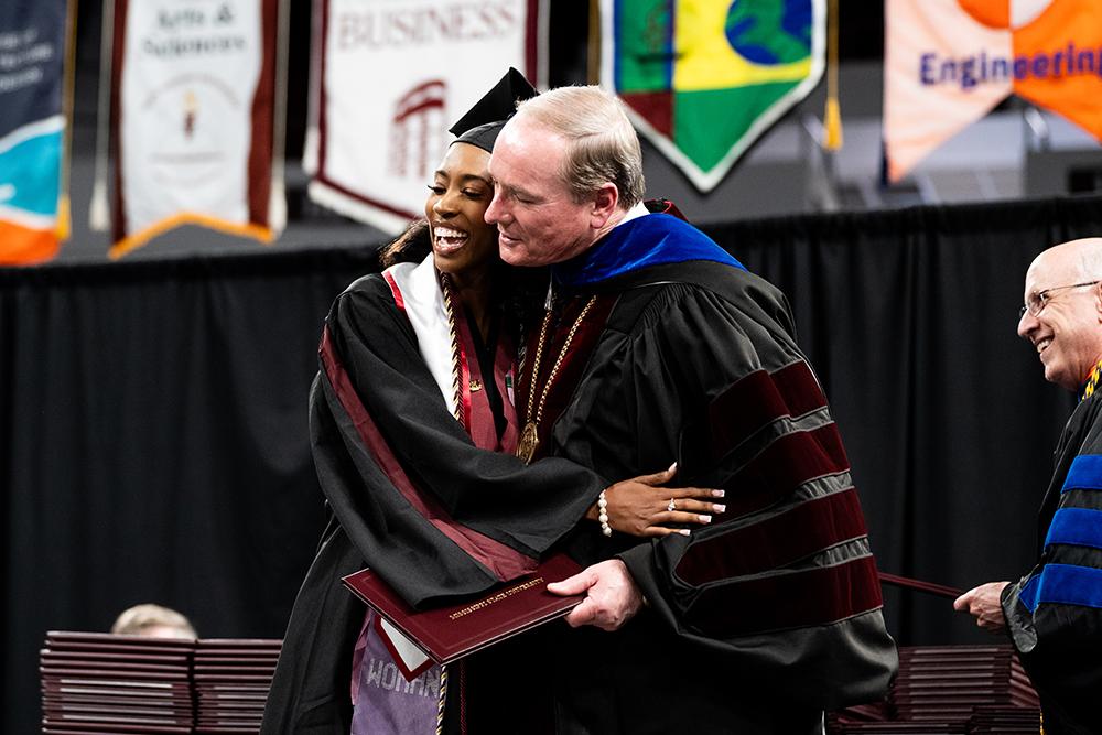 MSU President Mark E. Keenum hugs a student as he presents her degree during spring 2025 commencement in Starkville.