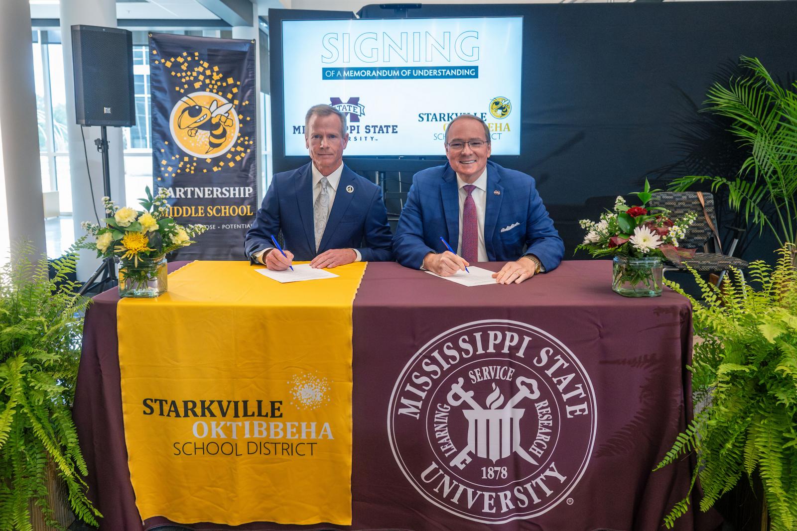 two men sit at yellow and maroon table