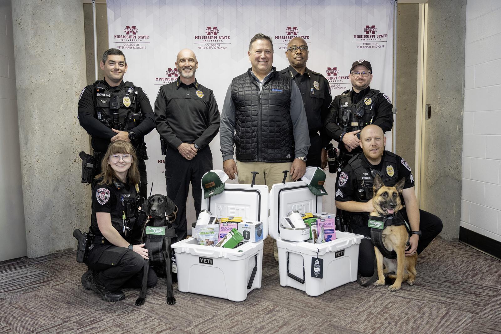 Mississippi State College of Veterinary Medicine alumnus and Nutramax Laboratories Veterinary Sciences Inc. CEO Dr. Todd Henderson, center, is pictured today [Dec. 11] after officially presenting the MSU Police Department with generous support for K-9 officers. Officers include, front left, Officer Makenna Foster with K-9 Quinn; back from left, Officer William Bowling, Assistant Chief Brian Locke, Chief Kenneth Rogers and Officer Bradley Frost; front right, Sgt. Patrick Jenkins with K-9 Padi.