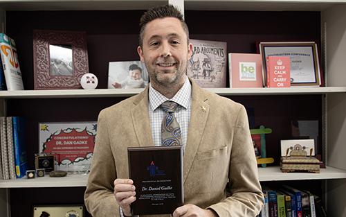 Daniel Gadke holds an award in his office.