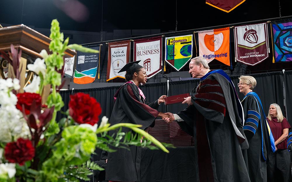 Mississippi State President Mark E. Keenum congratulates a new Bulldog graduate during commencement activities Thursday [May 14] at Humphrey Coliseum.